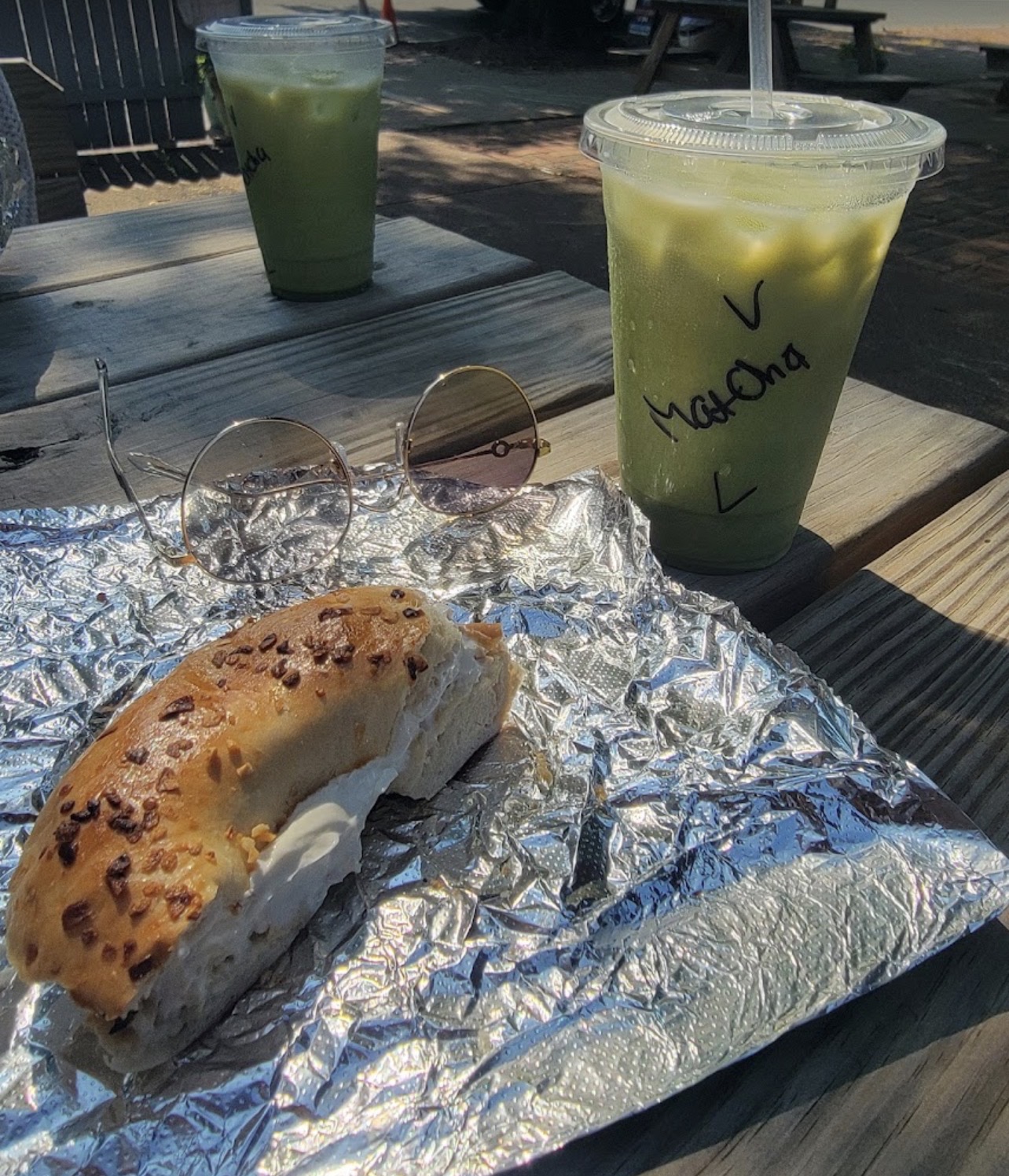 Iced matcha latte with an everything bagel on our outdoor picnic table